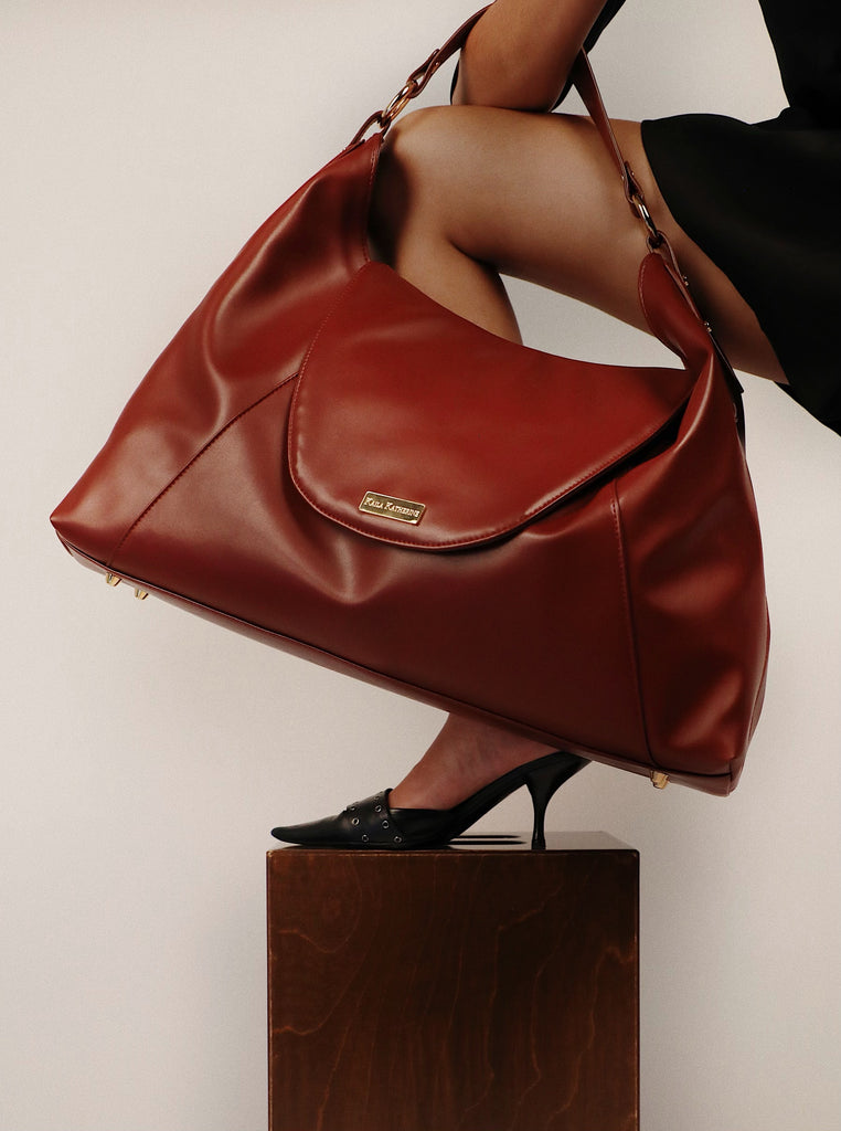 ruby colored kaila katherine vegan leather boho bag held over leg wearing high heel shoe